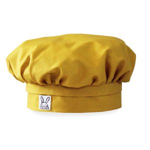 Une toque pour enfant de couleur jaune curry. Il s'ajuste pour toutes les têtes d'enfant à l'aide d'un élastique.