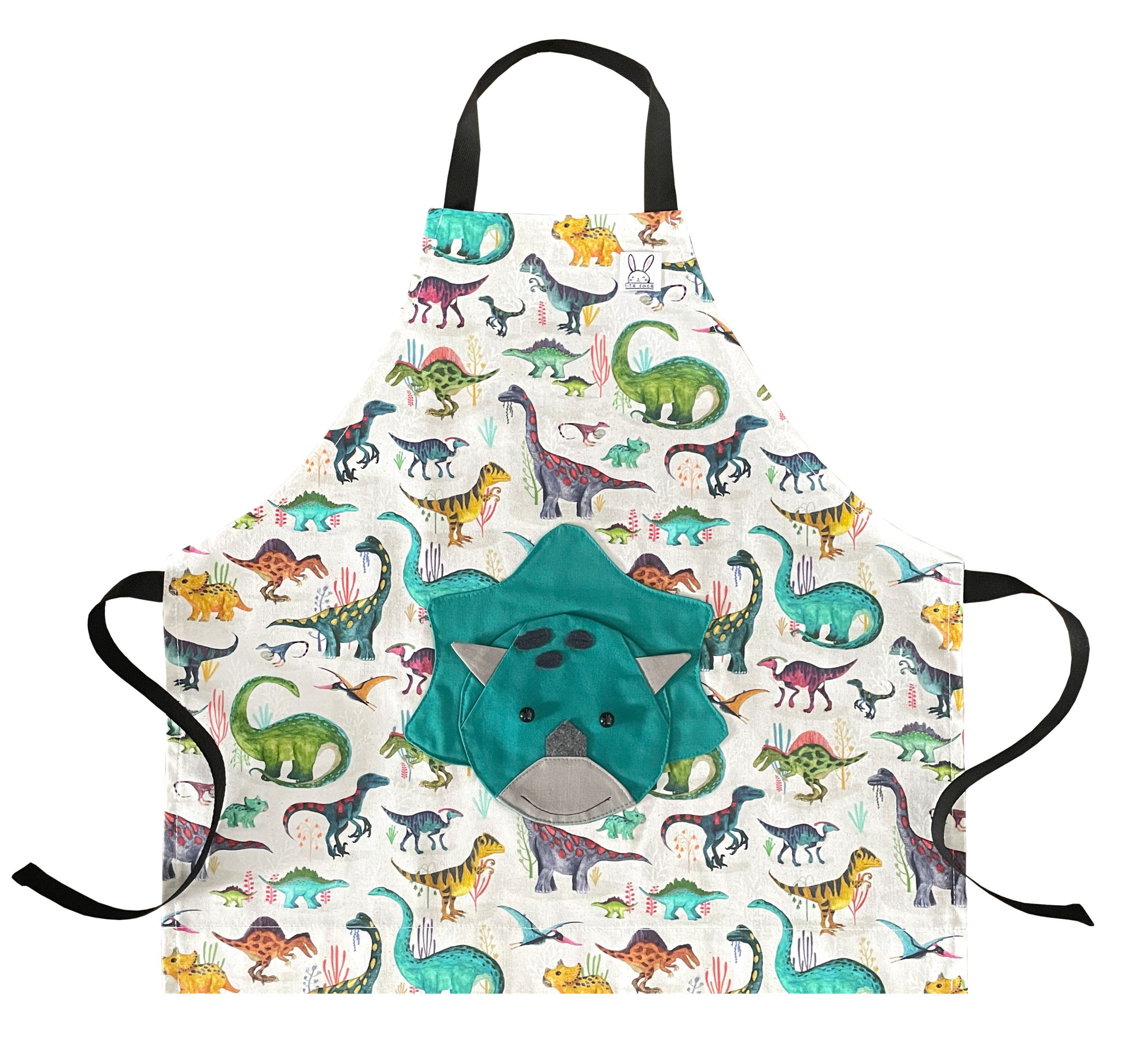 Tablier pour enfant à motif ''Dinosaures''. Doté d'une poche amusante au devant en forme d'un tricératops. Le tablier est ajustable à l'encolure à l'aide de boutons pressions. Il est offert en 2 grandeurs. Fabriqué au Québec.