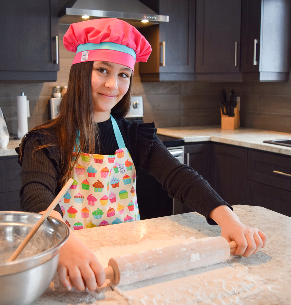 Ensemble de ''mini-chef'' pour faire fureur dans la cuisine! Le tablier s'ajuste à l'encolure à l'aide de boutons pressions. Le tablier à imprimé de cupcakes à une poche au devant en forme d'un gros gâteau. Le chapeau de cuisine est confortable et s'ajuste à toutes les têtes d'enfants à l'aide d'un élastique. Fabriqué au Québec.