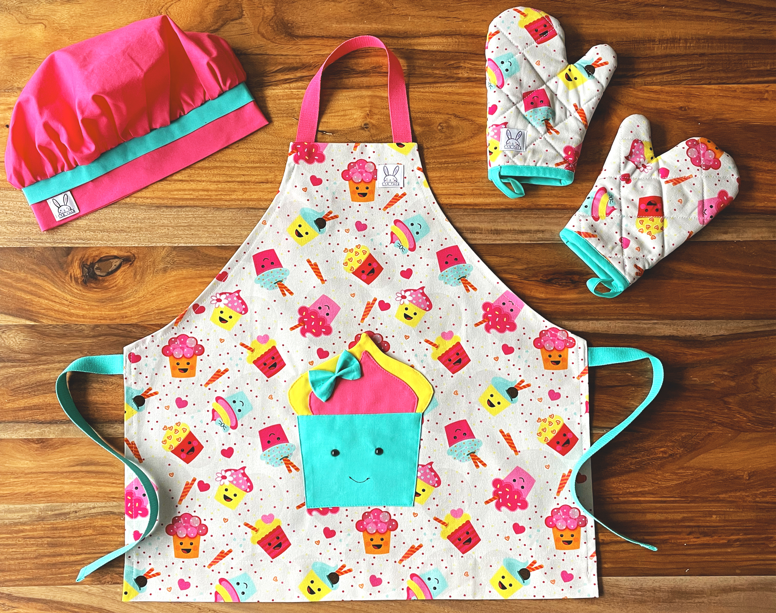 Ensemble de ''mini-chef'' pour faire fureur dans la cuisine ! Le tout comprend: 1 tablier, 1 paire de mitaine et 1 chapeau ajustable. Le tablier s'ajuste à l'encolure avec des boutons pressions. Une poche amusante au devant. Produits fait au Québec. Les mitaines de four sont isolées. Il y a des ganses pour les accrocher sur un crochet. La toque fuchsia est ajustable à l'aide d'un élastique.